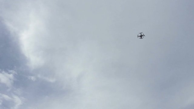 Quadrocopter unmanned camera hovers in bright blue sky .