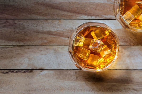 Glass of whiskey with ice on wooden background, Top view 