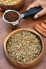 Freshly ground coffee beans in a metal filter and coffee beans with cinnamon for background