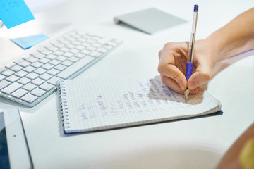 Woman hands with pen writing on notebook at office