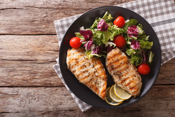 roasted Chicken breast with mix salad of chicory, tomatoes and lettuce close-up. horizontal top view