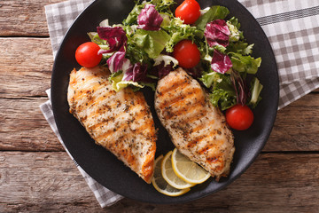 Grilled chicken breast with salad of chicory, tomatoes and lettuce close-up. horizontal top view
