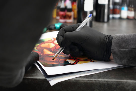Salon tatuażu, artysta projektuje wz&oacute;r. 