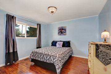 Blue walls bedroom with antique chest of drawers and wood flooring