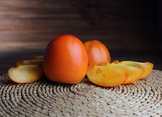 свежая хурма,порезанная дольками на соломенной салфетке