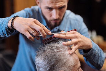 Close up of young male hairdresser cutting hair