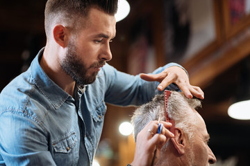 Low angle of handsome hairdresser doing his job