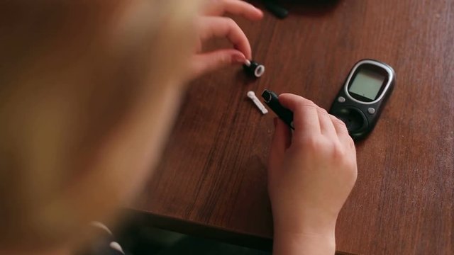 The girl changes the needle into the syringe handle to the glucometer. Monitoring blood sugar at home. Insulin. Diabetes.