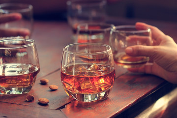 Whiskey bourbon in a glass with ice on wooden table background