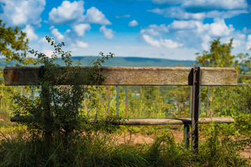 Old wooden bench in front of a panorama and a sky with clouds