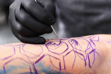 Etapy tworzenia tatuażu. Tatuaż,tatuator wykonuje tatuaż na ręce mężczyzny.