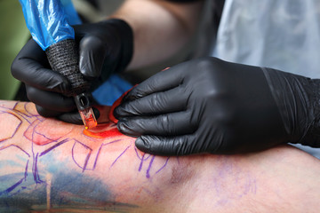 Maszynka do tatuażu. Tatuator tatuuje kolorowy tatuaż na ręku mężczyzny