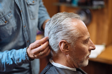 Barber styling hair of senior client