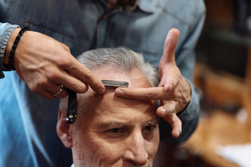 Close-up of senior man having haircut at barbershop