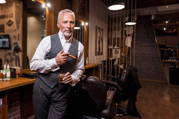 Senior gentleman standing with glass and cigar