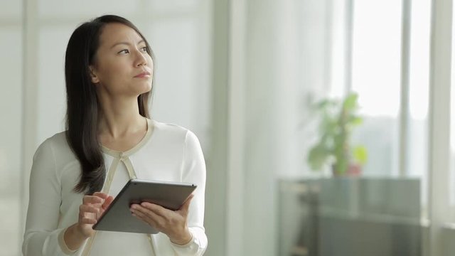 MS SELECTIVE FOCUS Woman looks up from a digital tablet, thinking / Singapore