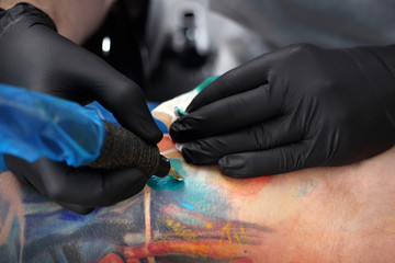 Tatuator tatuuje kolorowy tatuaż na ręku mężczyzny