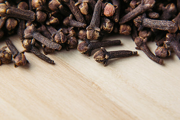 Clove spice closeup on wooden beige background. Decorative border of buds clove spice on wood board.