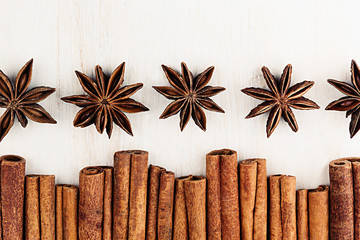Cinnamon sticks and anise star closeup on white wood background. Christmas decorative border of cinnamon sticks spice. Top view.