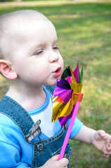 Cute little boy blowing on a pinwheel