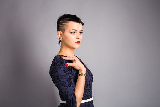 Portrait of young beautiful woman with stylish short haircut over grey background
