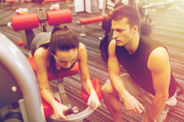 young woman with trainer exercising on gym machine