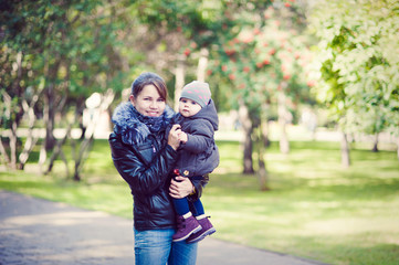 Mother keeps baby on hand for a walk in the Park, cool weather, horizontal.