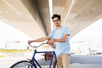hipster man with fixed gear bike under bridge
