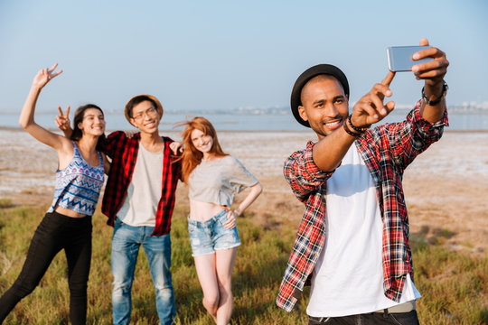 Happy man standing and taking selfie with his friends outdoors
