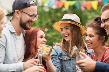 happy friends clinking glasses at summer garden