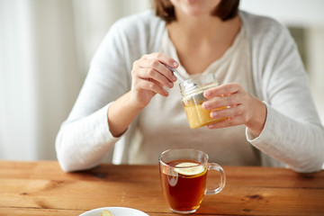 close up of ill woman drinking tea with honey