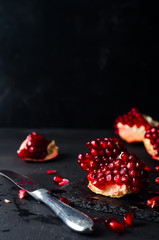 Pomegranates and pomegranate seeds on a dark background