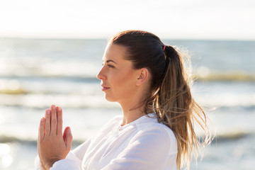 woman making yoga on summer beach