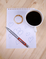 Cup of coffee and pen on the wooden table