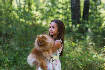 Girl with her favorite dog walking in the forest in summer