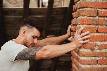 Fototapeta premium Attractive guy next to a brick wall
