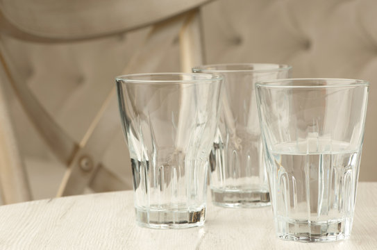 Three empty glass transparent cup on the table against the background of the chair and sofa