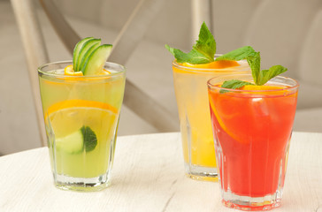 three glass of transparent glass with juice and lemon on the table against the background of the chair and sofa