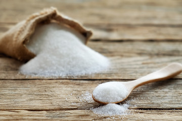White sugar in wood spoon on wood table soft focus(selective focus)