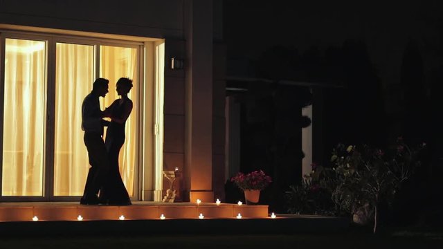 WS Silhouette of couple dancing on patio at night / India