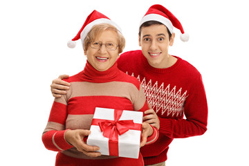 Elderly woman and young man wearing Santa hats with Christmas pr