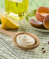 Natural mayonnaise sauce in the wooden spoon and its ingredient