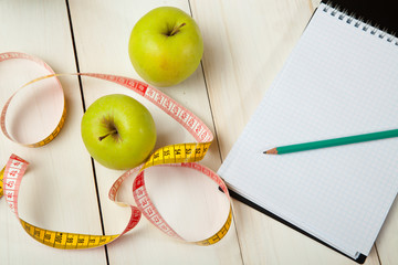 Green apples with measuring tape on a white wooden table