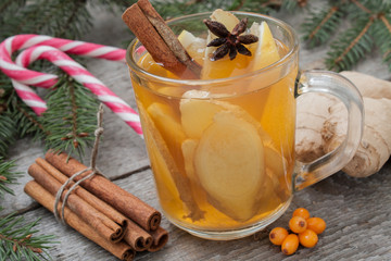 Christmas composition. Spruce branches, candy cane, warming tea with ginger and lemon,  dried oranges, grapefruit, cinnamon, star anise, pomegranates on a wooden background.