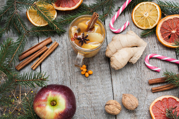 Christmas composition. Spruce branches, candy cane, warming tea with ginger and lemon,  dried oranges, grapefruit, cinnamon, star anise, pomegranates on a wooden background.