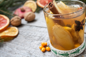 Christmas composition. Spruce branches, candy cane, warming tea with ginger and lemon,  dried oranges, grapefruit, cinnamon, star anise, pomegranates on a wooden background.