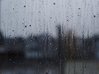 Regentropfen auf Fensterscheibe mit Gebäuden im Hintergrund