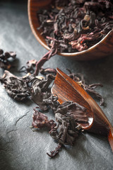 Hibiscus tea in the wooden bowl on the dark stone table vertical