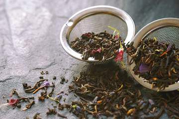 Tea with flower petal in the strainer on the stone background horizontal