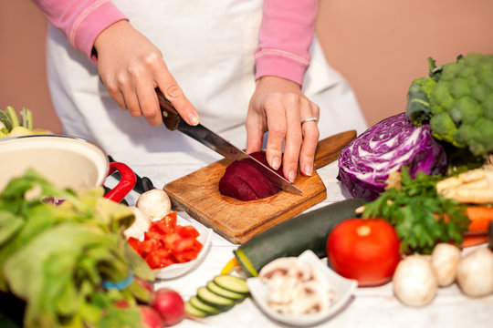 Housewife cutting a beetroot with a knife, vegetable cutting in